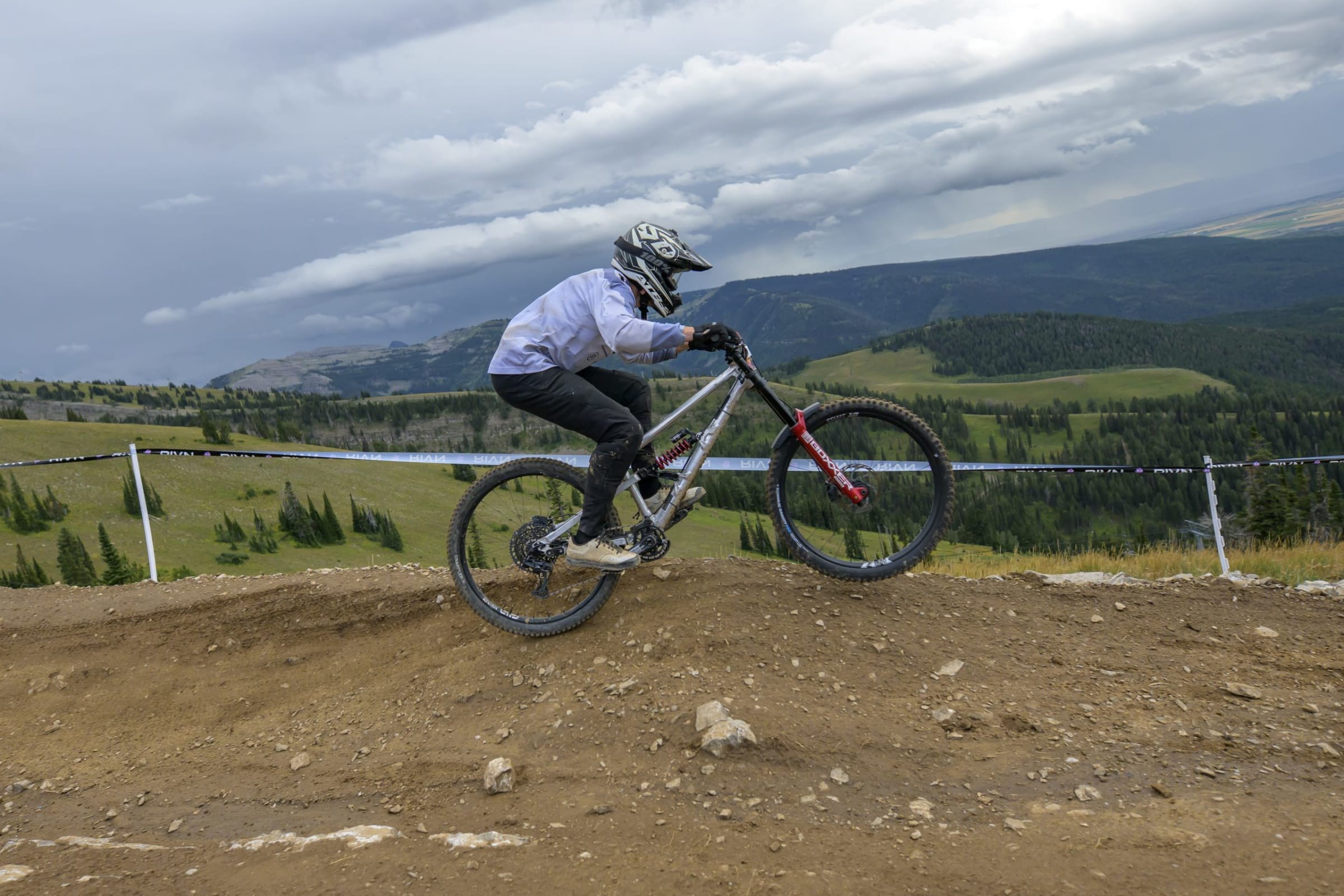 Racer carving under a storm sky above the valley at Grand Targhee